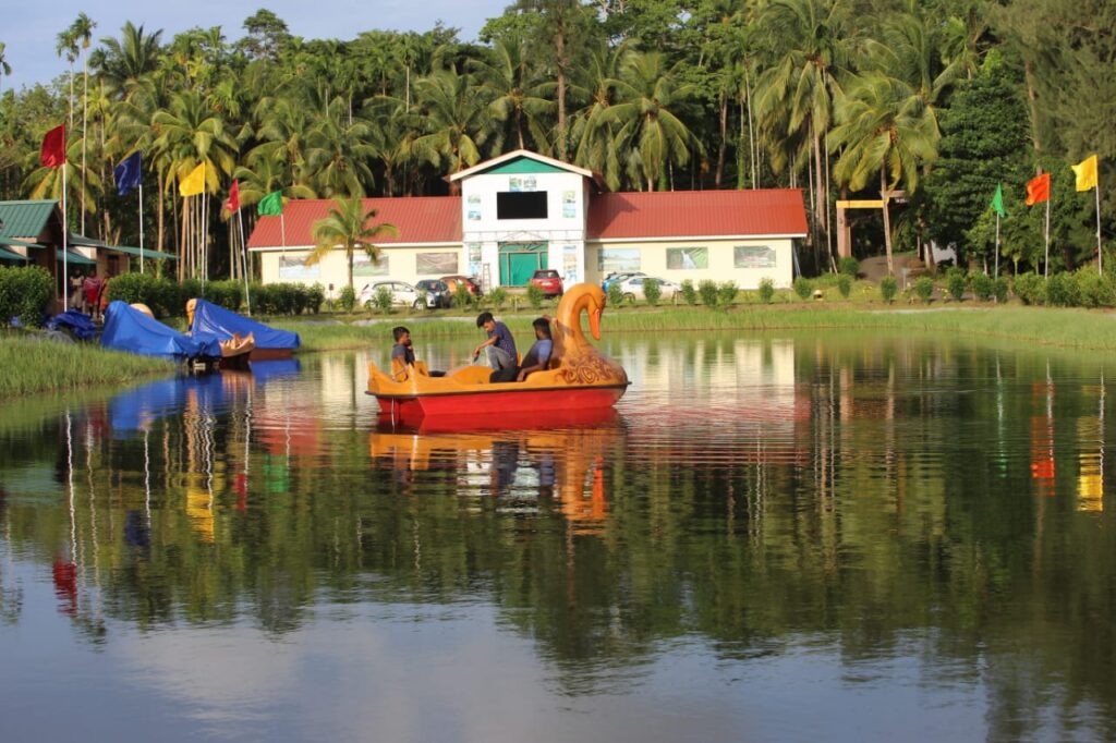 Day view of Lush Green Retreat with boating pond, main building and tropical greenery